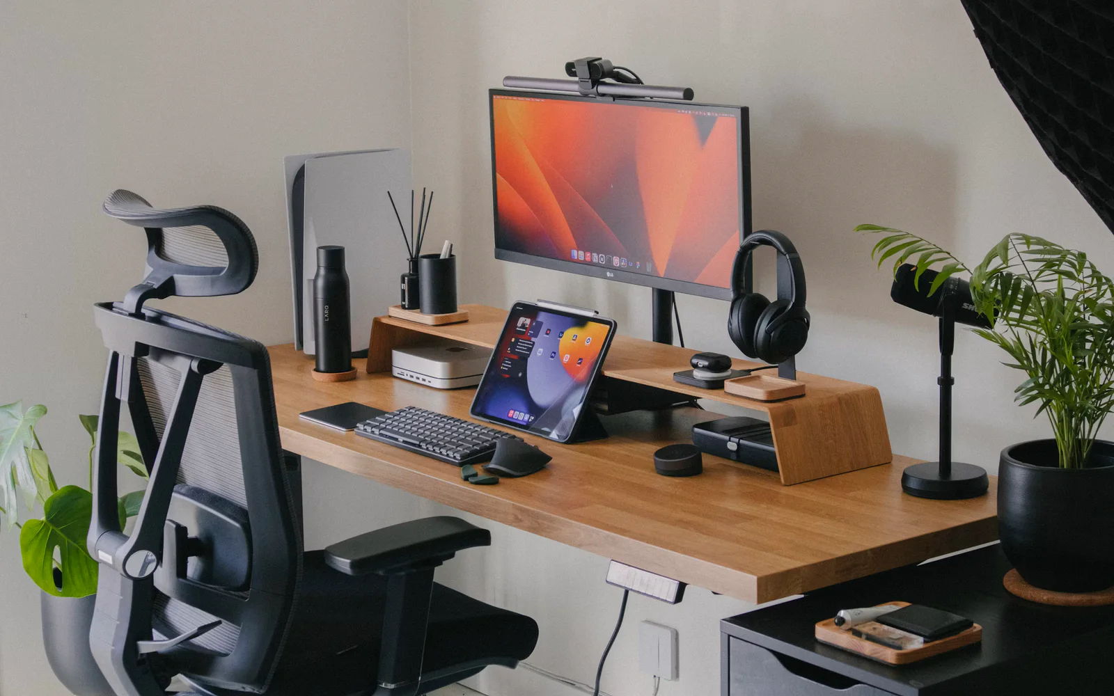 Editorial tool-testing desk with monitor, tablet, headphones, and plants